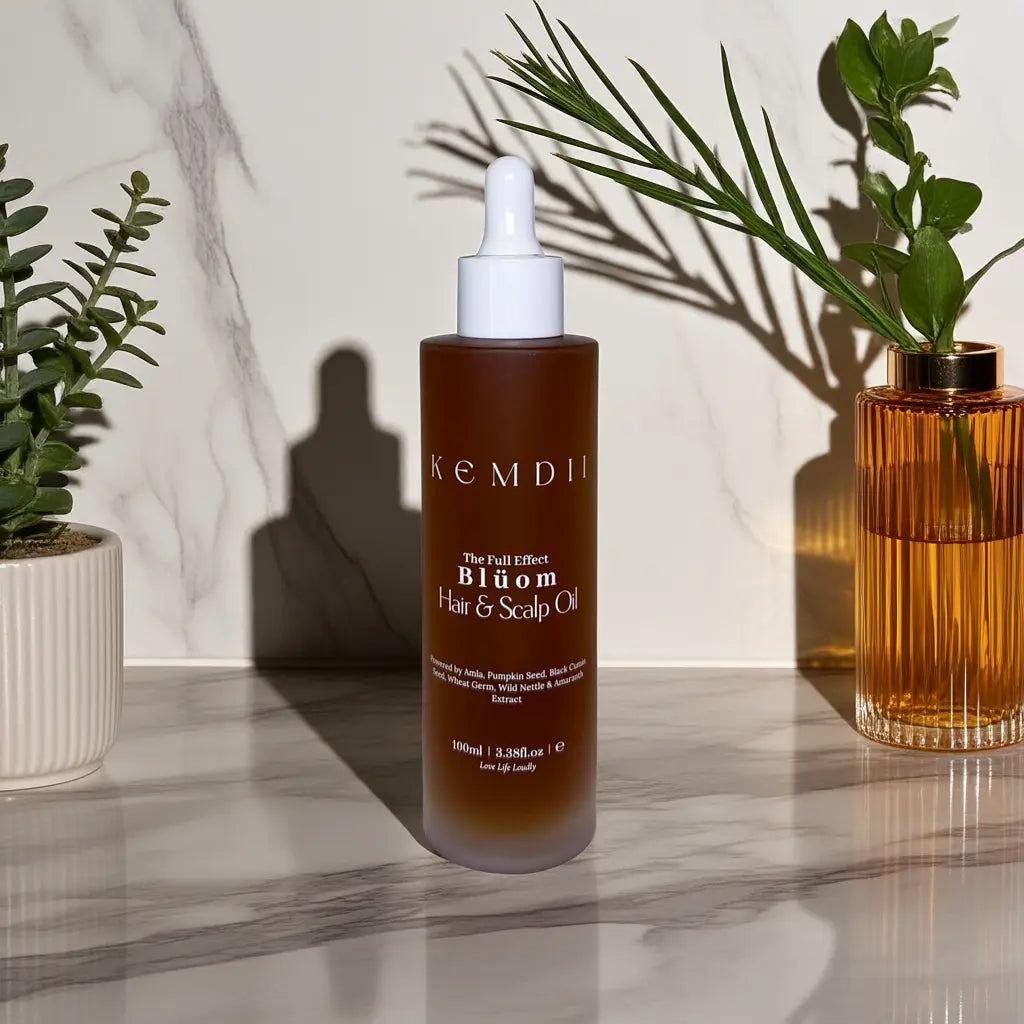 Lifestyle image of KEMDII Blüom Hair & Scalp Growth Oil with amber glass and indoor plants- luxurious daily oil for thinning edges and scalp health