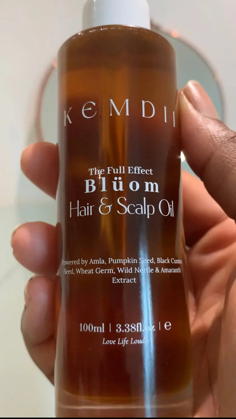 KEMDII Blüom Hair & Scalp Oil held in hand, showing close-up of bottle with amla, pumpkin seed, and black cumin for hair growth and scalp care