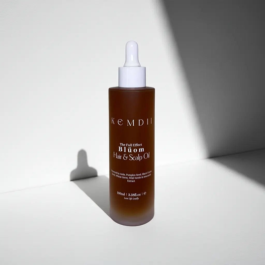 Minimalist product shot of KEMDII Blüom Hair & Scalp Oil with dramatic shadows on a white background