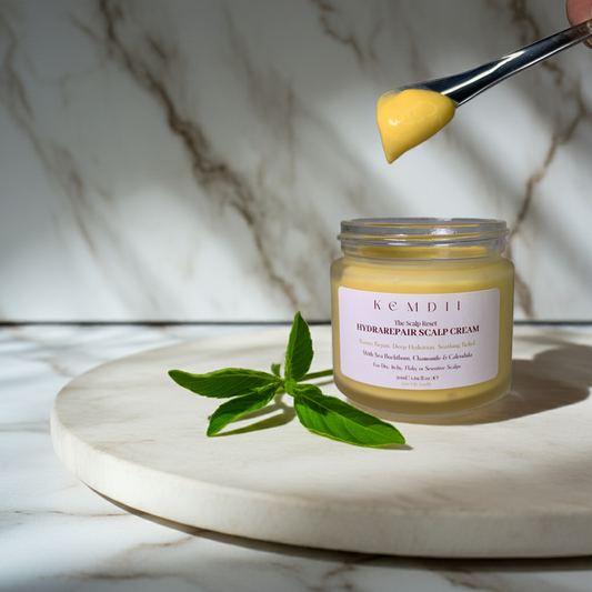 KEMDII HydraRepair Scalp Cream shown in jar with a spoon lifting the rich cream texture, illustrating how to apply the scalp treatment to dry or sensitive scalps